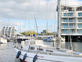 En lysthavn med fortøjede både, en bygning med flere etager og en klar himmel.