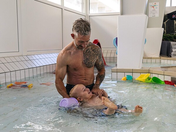 A man in a swimming pool with a child.