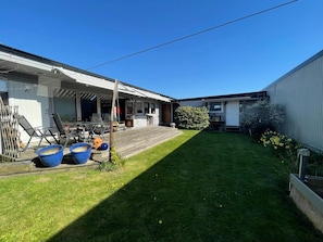 A residential property with a covered patio, a lawn, and a small garden area.