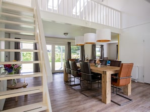 Uma sala de jantar espaçosa com teto alto, mesa de madeira e cadeiras modernas.