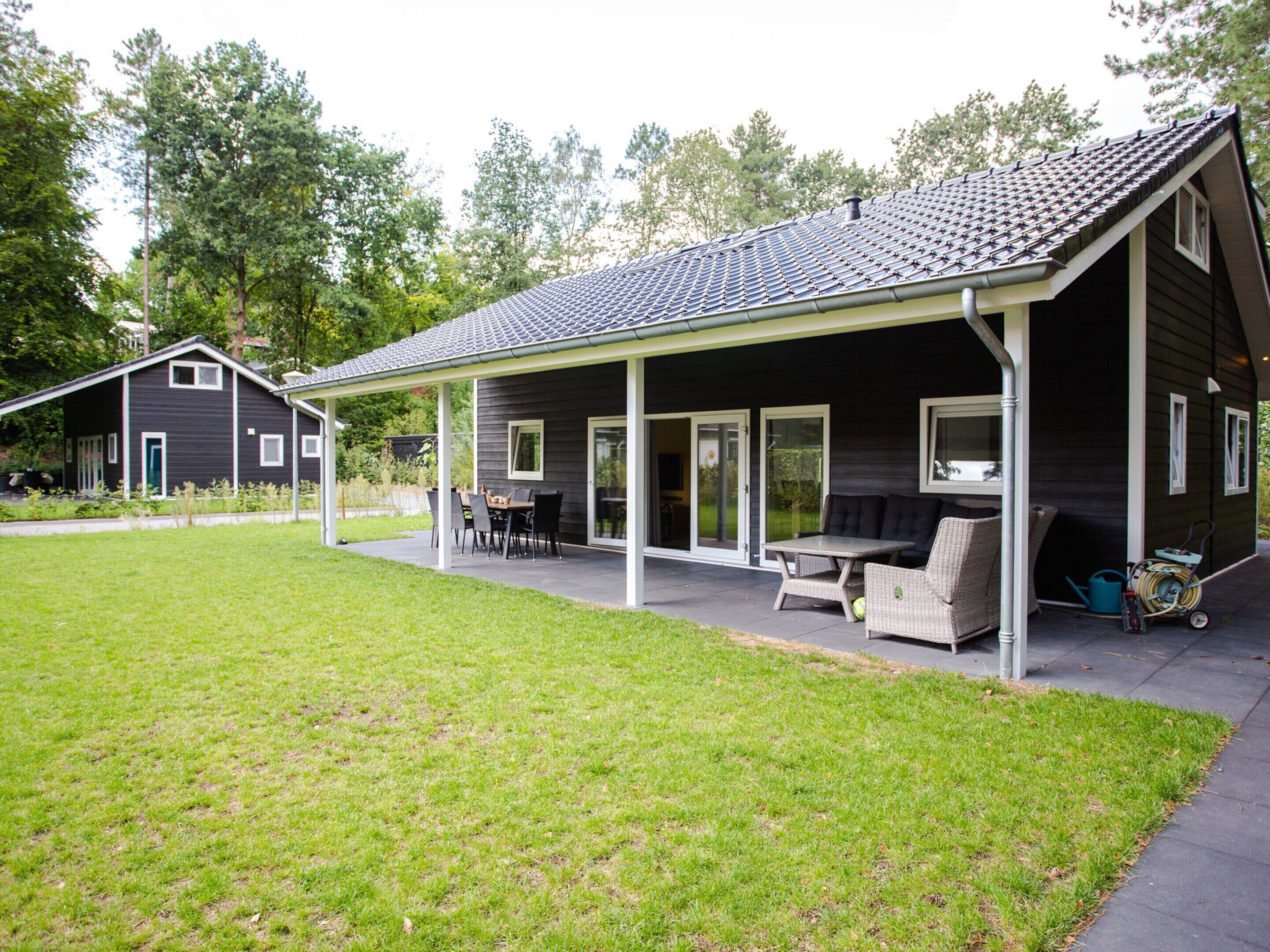 A house with a covered patio, a lawn, and a neighboring building.