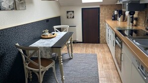 A compact kitchen with a dining area, featuring a skylight, a coffee machine, and a microwave. - Mechthild and Hans-jurgen Geschwind (Schleiden)