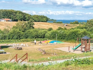 A park with picnic tables, a playground, and a view of the sea. - 7 Person Holiday Park Home in Aabenraa (Aabenraa)