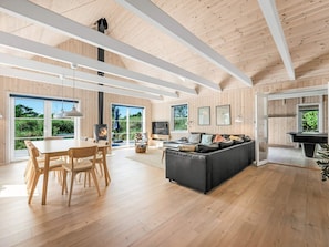 A spacious living area with a wooden floor, a dining table with chairs, a sofa, and a television. - 5 Star Holiday Home in Henne (Henne)