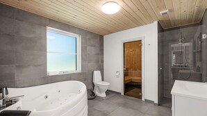 Et stilfuldt badeværelse med et stort badekar, toilet og bruseområde.