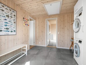 A modern interior with a wooden wall, a poster of fish, a washing machine, and a bench. - 5 Star Holiday Home in Henne (Henne)