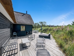 A wooden deck with outdoor seating and a thatched-roof building. - 5 Star Holiday Home in Henne (Henne)