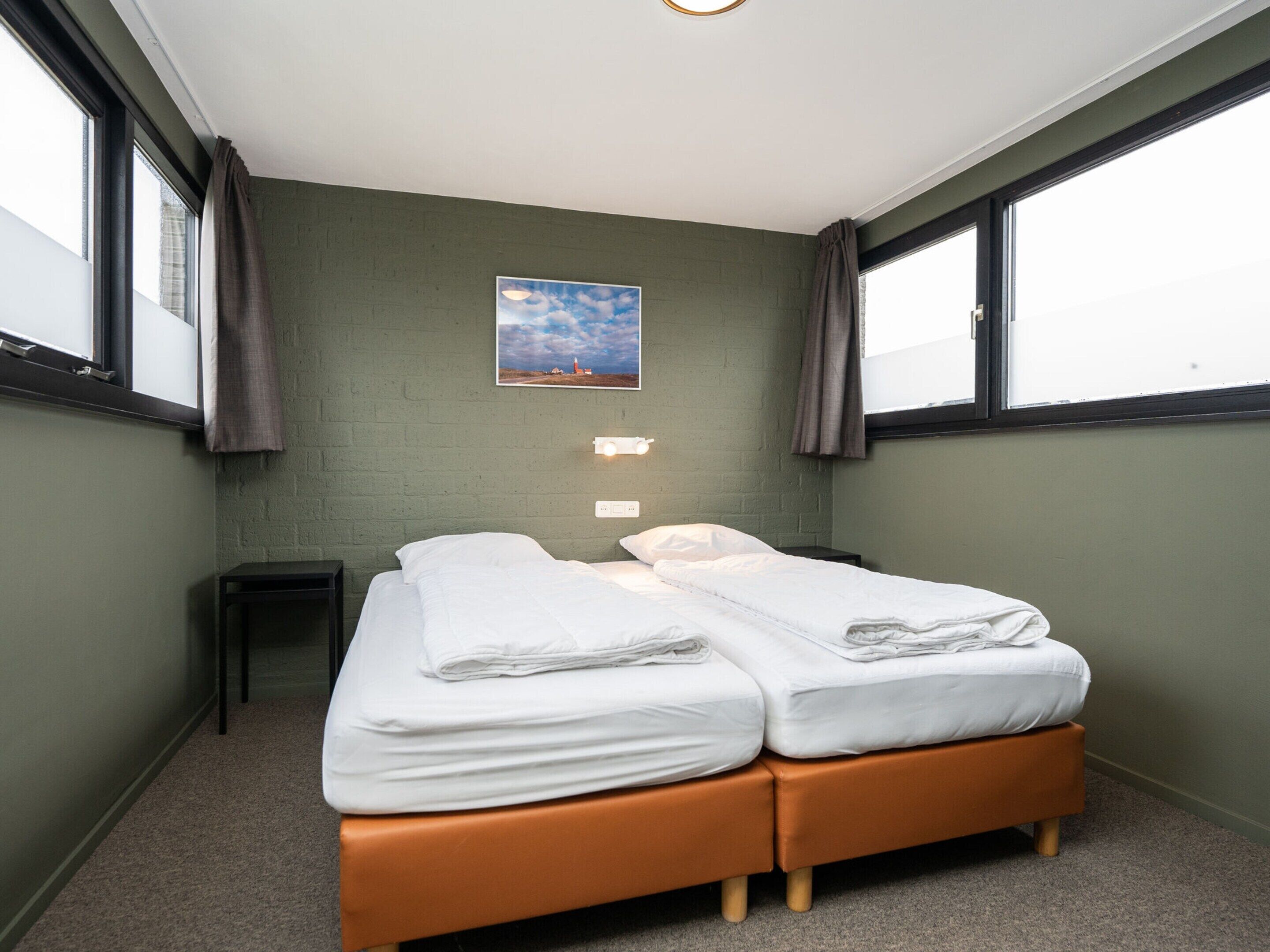 A room with two beds, a small table, and a painting on the wall.