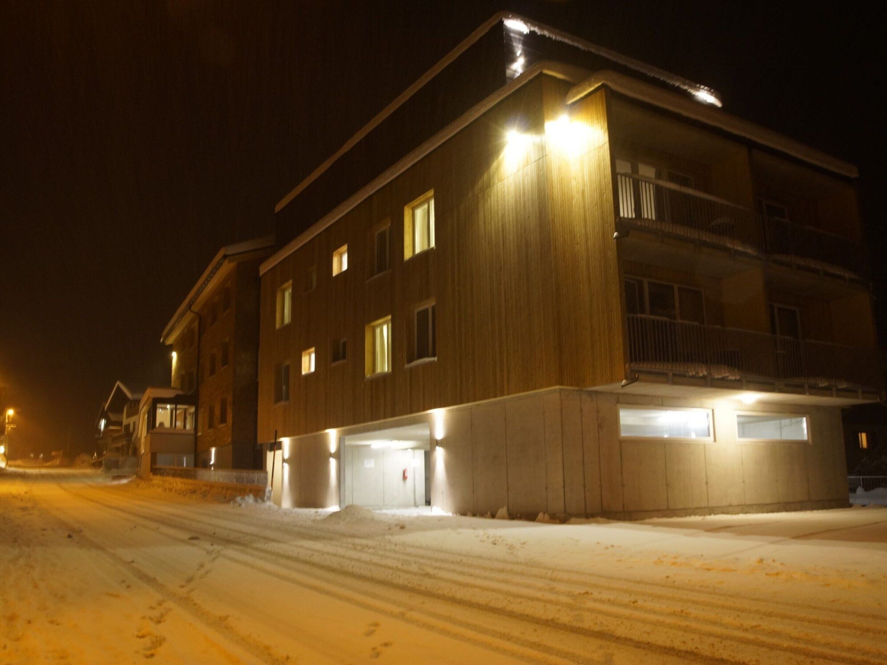 Un edificio de varios pisos con techo plano y suelo cubierto de nieve.