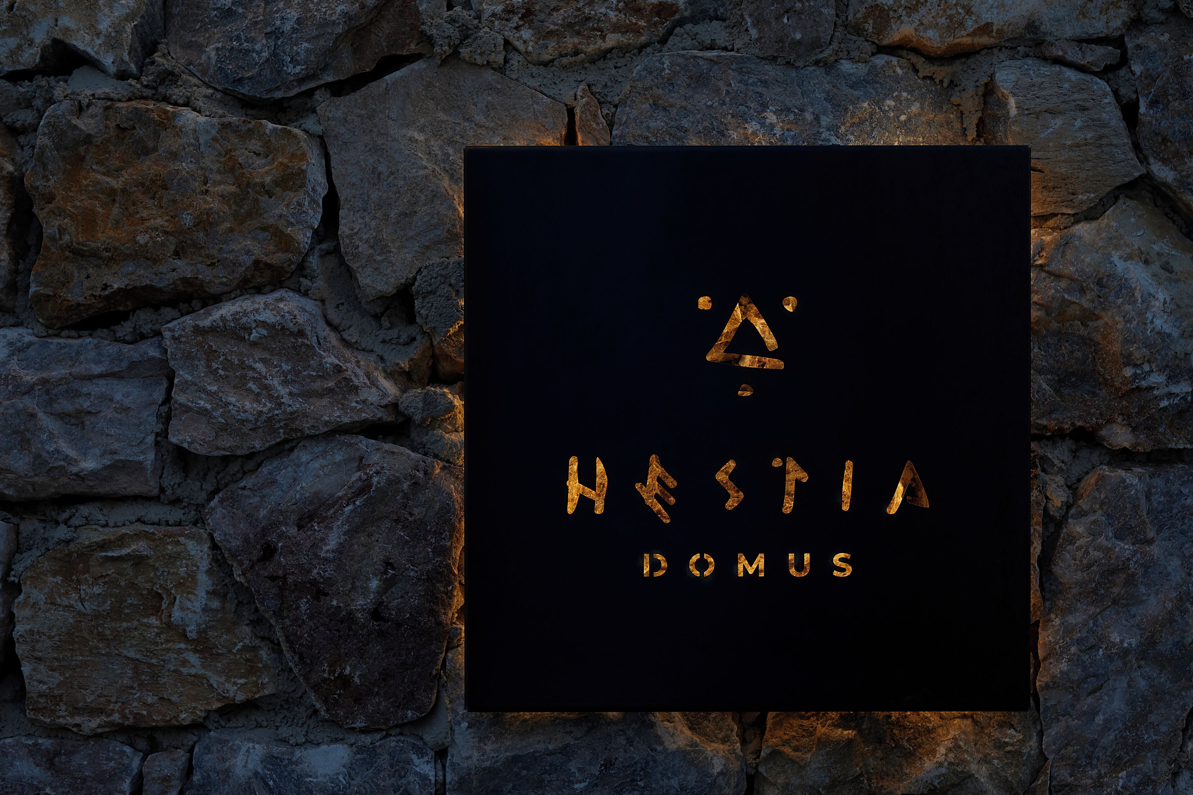 A sign with the text 'Hestia Domus' against a stone wall background.