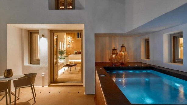 Una piscina interior moderna con vistas a una habitación acogedora y un comedor.