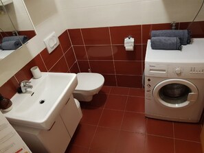 A bathroom with a sink, toilet, and washing machine. - Apartment Aurelia Arena (Zagreb)