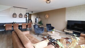 Una sala de estar moderna con un sofá, un televisor y un comedor con sillas y una mesa.