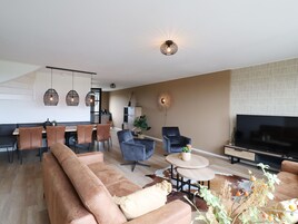 Una sala de estar moderna con un sofá, un televisor y un comedor con sillas y una mesa.
