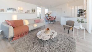 A modern living room with a sofa, a coffee table, and a dining area with chairs. - Dyke-view Stay With Terrace (Wemeldinge)
