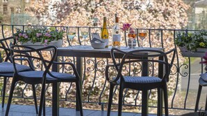 Um terraço com uma mesa posta para dois, incluindo uma garrafa de vinho, copos e um cardápio.
