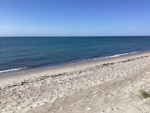 A beach with a clear sky, calm sea, and a sandy shore. - Seaside Charm in Gedser - By Traum Ferienwohnungen (Gedser)
