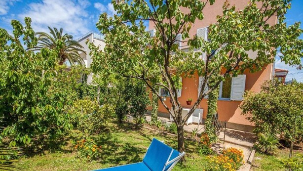 Una silla azul de descanso en un jardín, con un edificio al fondo.