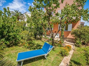 A blue lounge chair in a garden with a building in the background. - Apartments Amalia - Two Bedroom Apartment With Roofed Terrace (Zadar)
