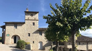 A stone building with a tower, arched doorways, and a small garden area.