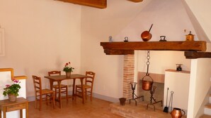 A cozy dining area with wooden furniture, a hanging pot rack, and a fireplace.