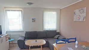 A compact living space with a sofa, a small table, a TV, and a window. - 08 am Haff Modern Retreat (Kamminke)