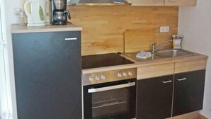 A compact kitchen with a stove, oven, and sink. - 08 am Haff Modern Retreat (Kamminke)