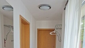 A narrow hallway with a wooden door, a ceiling light, and a window with curtains. - 08 am Haff Modern Retreat (Kamminke)