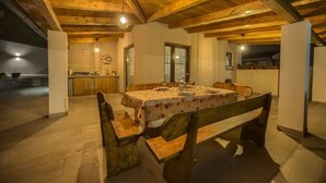 A dining area with a wooden table and benches, a kitchen in the background, and a high ceiling with exposed beams. - Villa G With Pool in Barban (Barban)