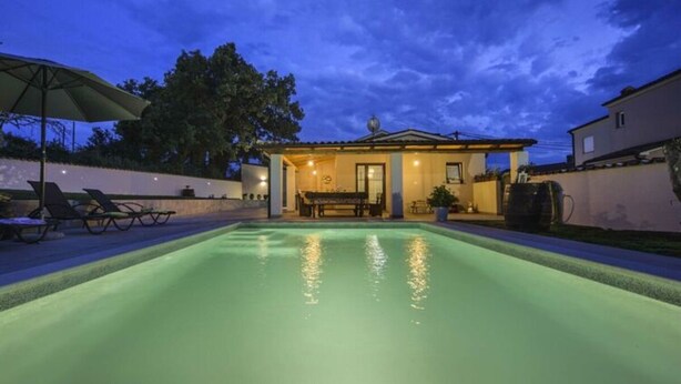 A swimming pool with a patio area, lounge chairs, and a building with a tiled roof. - Villa G With Pool in Barban (Barban)