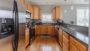 Een moderne keuken met houten kastjes, roestvrijstalen apparatuur en een groot raam voor natuurlijk licht.