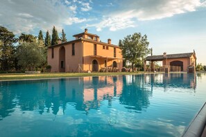 A large swimming pool with a building in the background. - Lavish Peccioli Villa (Peccioli)
