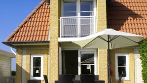 A two-story house with a patio area featuring a table and chairs under a large umbrella. - Villa "De Banjaard Zeeland" (Kamperland)