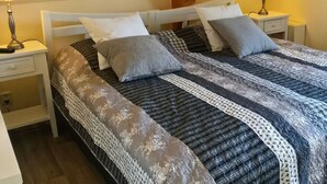 A neatly made bed with a patterned bedspread and pillows, flanked by bedside tables with lamps. - Villa "De Banjaard Zeeland" (Kamperland)