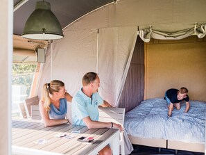 Eine Zelthütte mit einem Bett, einem Tisch mit Spielkarten und einer Hängelampe.