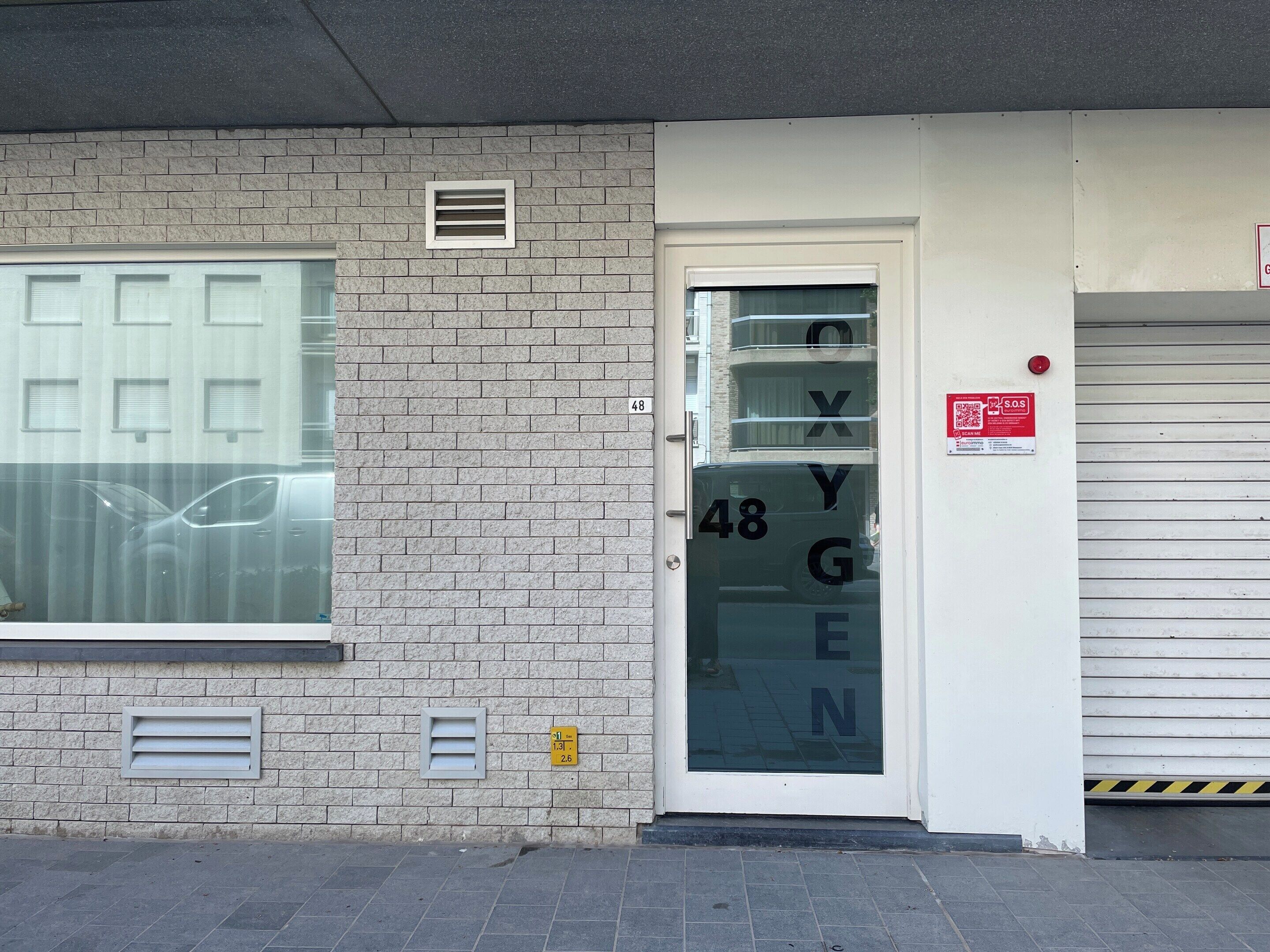 A building facade with a numbered door, a window with blinds, and a garage door.