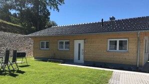 A single-story building with a tiled roof, a small front porch, and a grassy yard. - Baier Holiday House (Philippsreut)