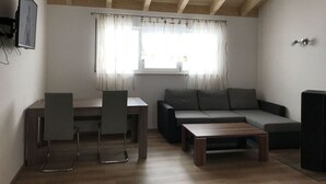 A modern living room with a wooden ceiling, a dining table with chairs, a sofa, and a coffee table. - Baier Holiday House (Philippsreut)