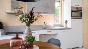 A modern kitchen with white cabinets, a built-in oven, and a window. - House for the Disabled, Holiday Park in Friesland (Akkrum)