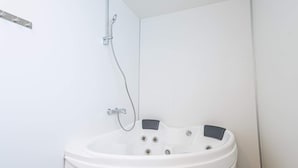 Kylpyhuone, jossa on erillinen kylpyamme, suihkupää ja wc.