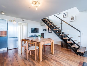 A modern kitchen with a built-in Bosch refrigerator, a dining area with a wooden table and chairs, and a black spiral staircase. - 5 Star Holiday Home in Hemmet (Hemmet)