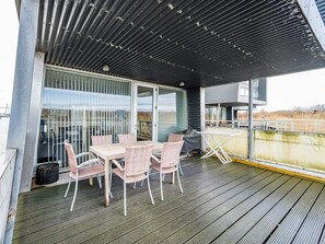 A covered outdoor area with a table and chairs, a grill, and a view of the surrounding landscape. - 5 Star Holiday Home in Hemmet (Hemmet)