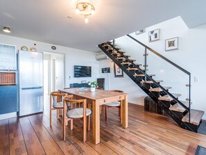 A modern kitchen with a Bosch refrigerator, a dining area with a wooden table and chairs, and a black staircase with glass railings. - 5 Star Holiday Home in Hemmet (Hemmet)