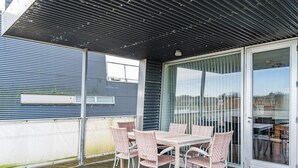 Ulkoterassi, jossa on pöytä ja tuoleja, liukuovet ja metallikatto.