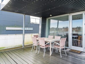 An outdoor patio with a table and chairs, a sliding glass door, and a metal roof. - 5 Star Holiday Home in Hemmet (Hemmet)