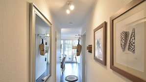 A hallway with framed artwork, a mirror, and a door leading to a room. - Beach House "blanker Hans" (Sylt)