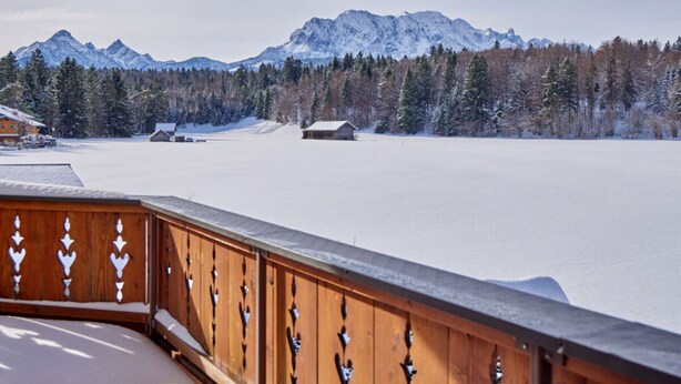 A wooden balcony overlooking a snowy landscape with mountains and trees. - Holiday Apartment "wetterstein" (Kruen)