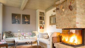 Een gezellige woonkamer met een open haard, een bank, een bijzettafeltje en een vloerkleed.