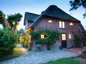 A traditional brick house with a steeply pitched roof, a front door, and a small garden area with a cobblestone path. - Apartment in Ettenheim (Witzwort)