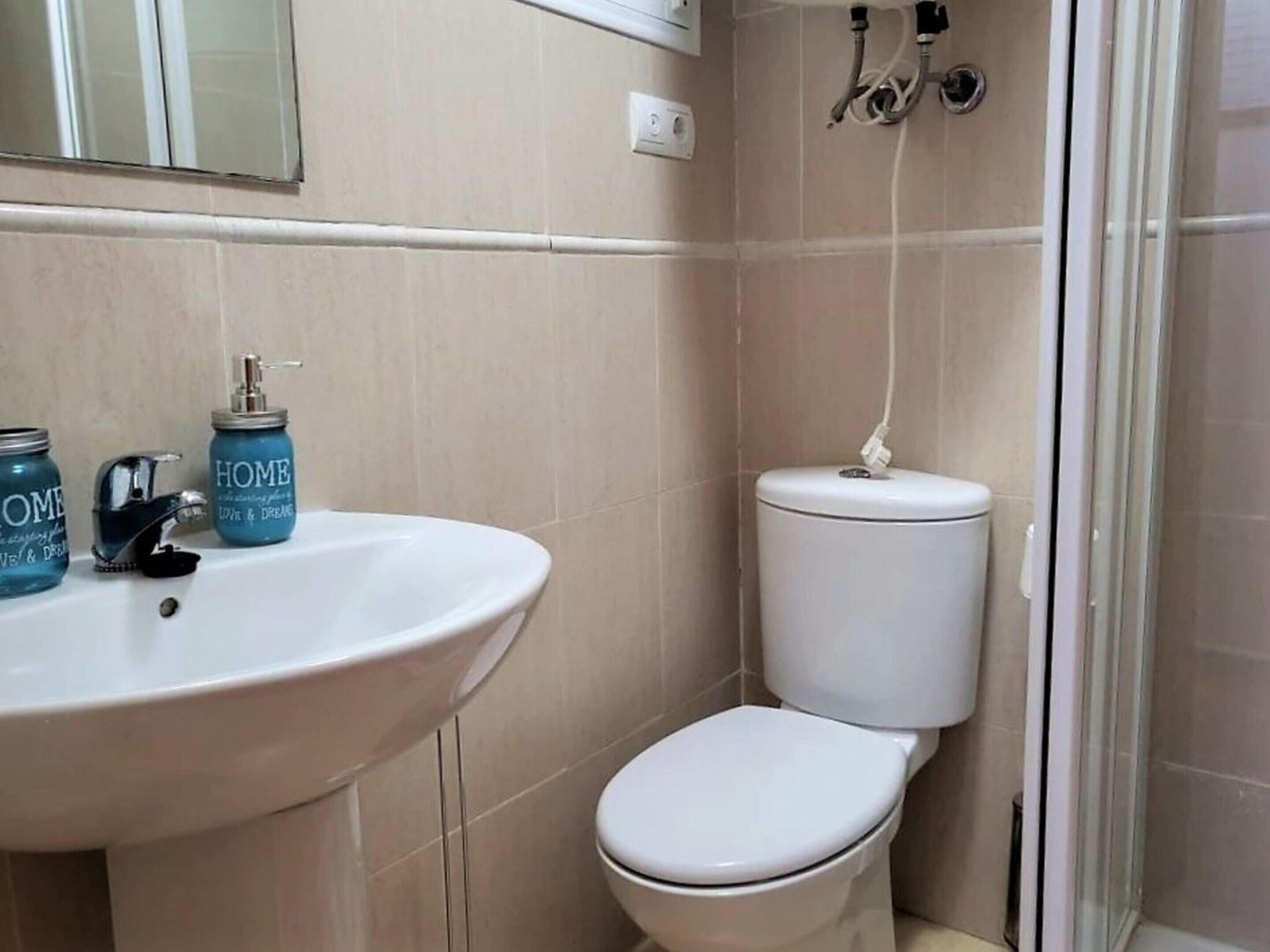 Une salle de bain avec un lavabo blanc, des toilettes et un espace douche.